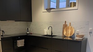 Eine moderne Küche mit dunklen Schränken, einer schwarzen Arbeitsplatte, einem eingebauten Ofen und einem Fenster über der Spüle.