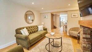 A living room with a green sofa, a round coffee table, and a fireplace. - Host Stay Ginger Bread Cottage (Middlesbrough)