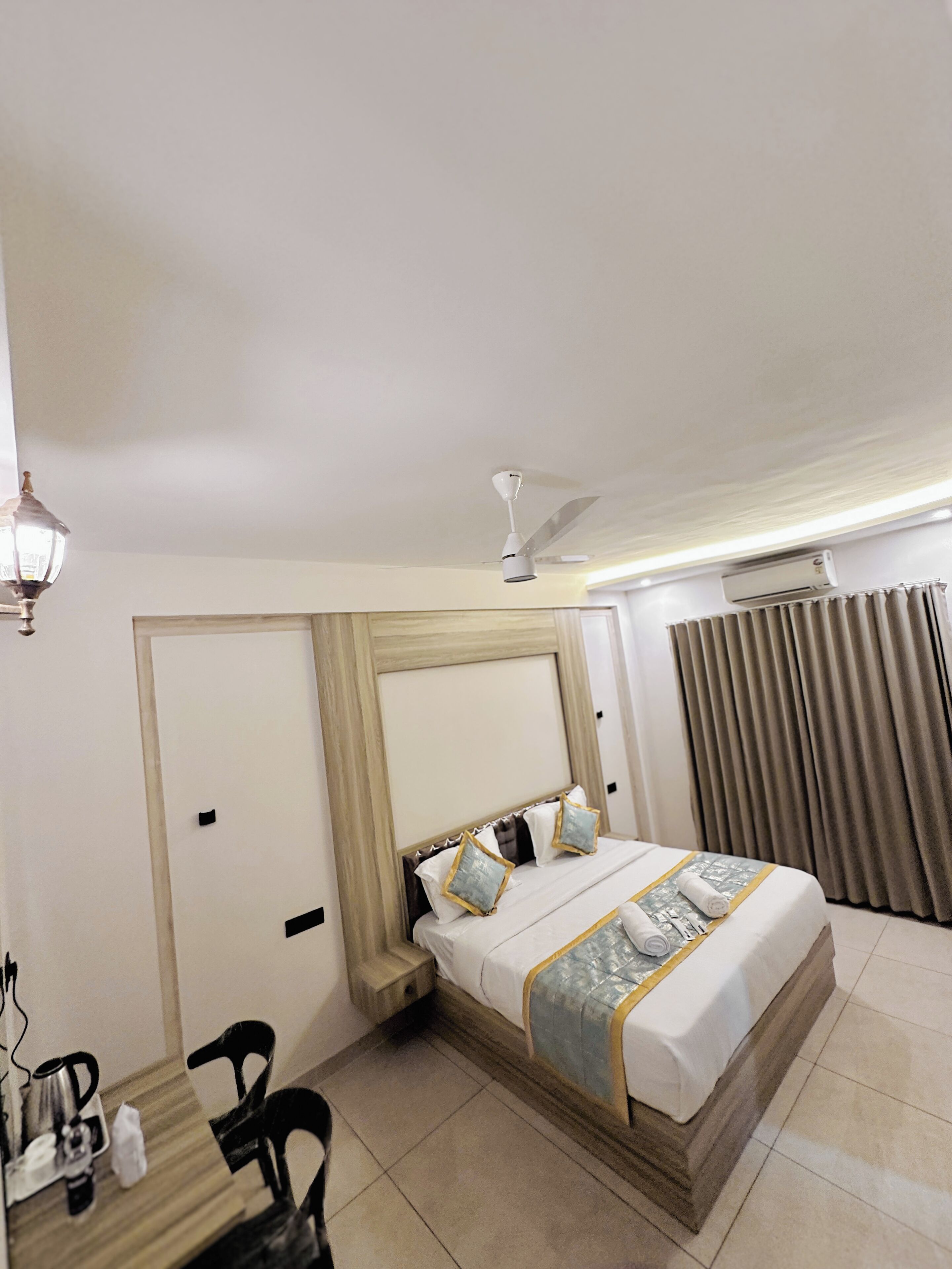 Une chambre d’hôtel équipée d’un lit, d’un bureau, d’une chaise, d’un ventilateur de plafond et d’un appareil de climatisation.