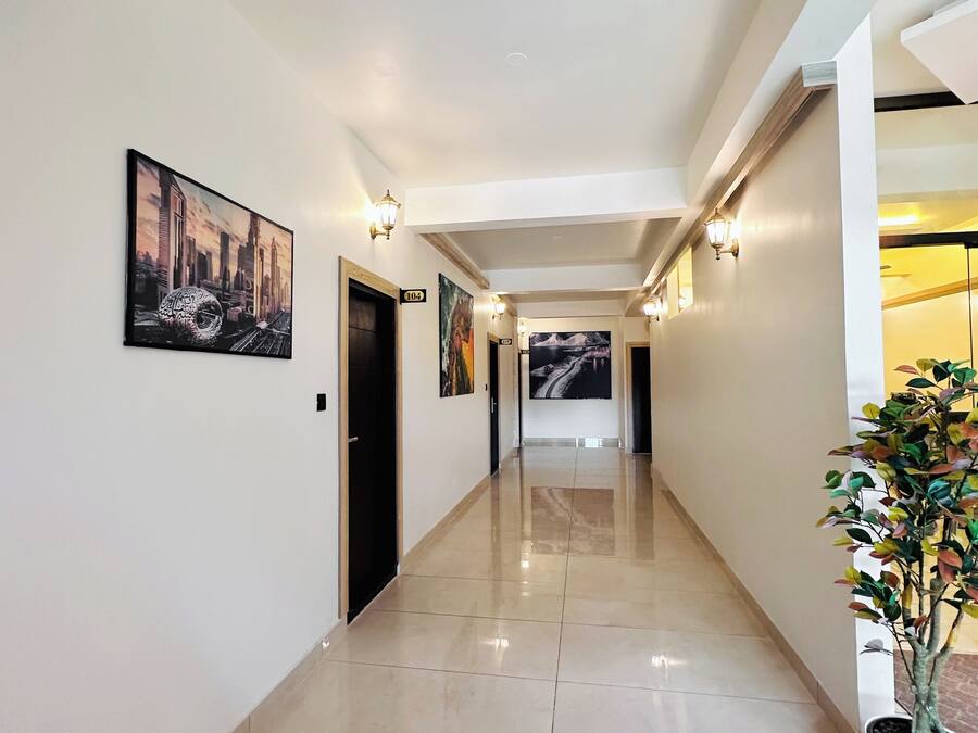 A hallway with a polished floor, wall-mounted artwork, and a potted plant.