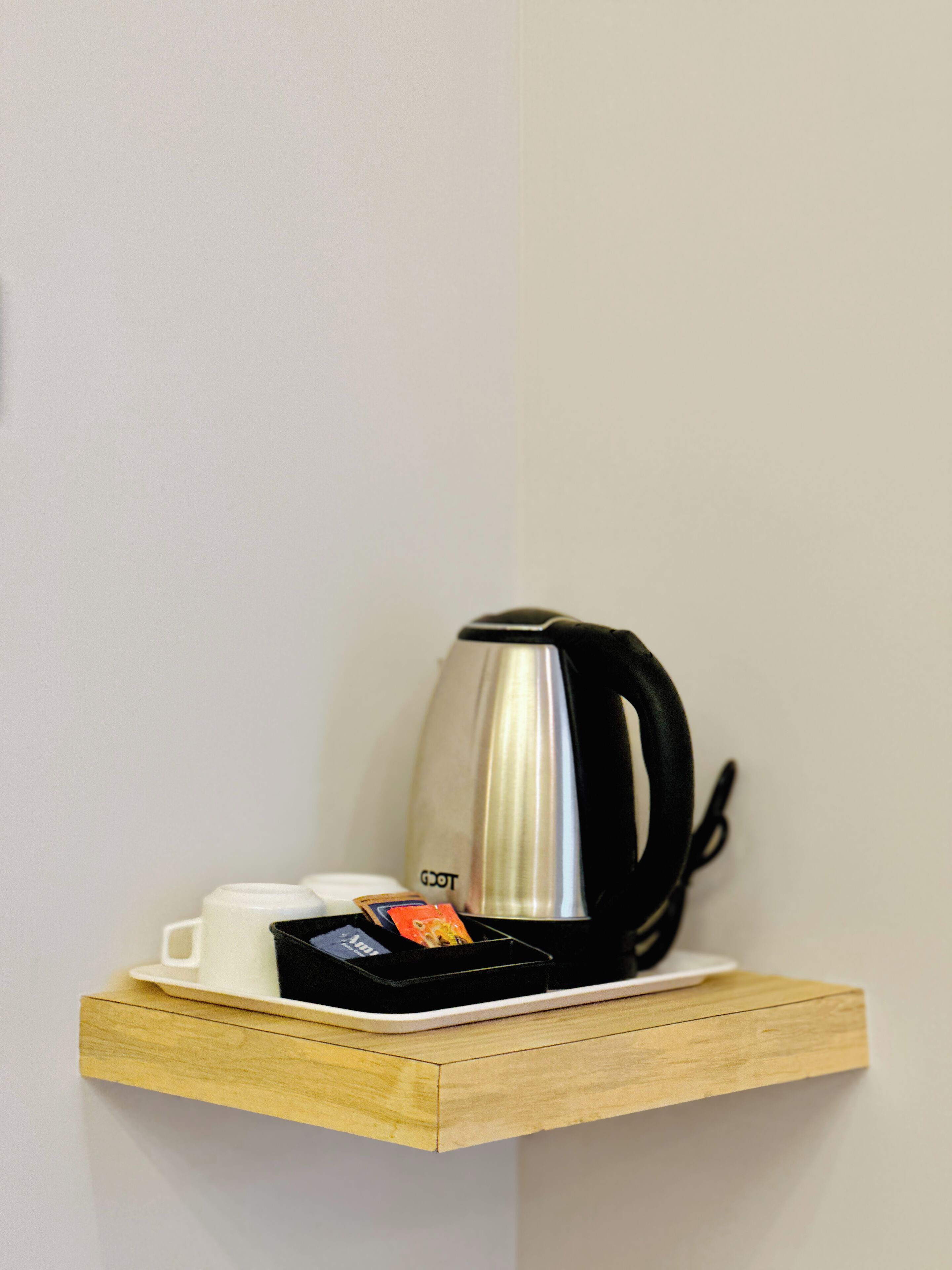 Un estante de madera con una cafetera, una taza y un porta tarjetas.