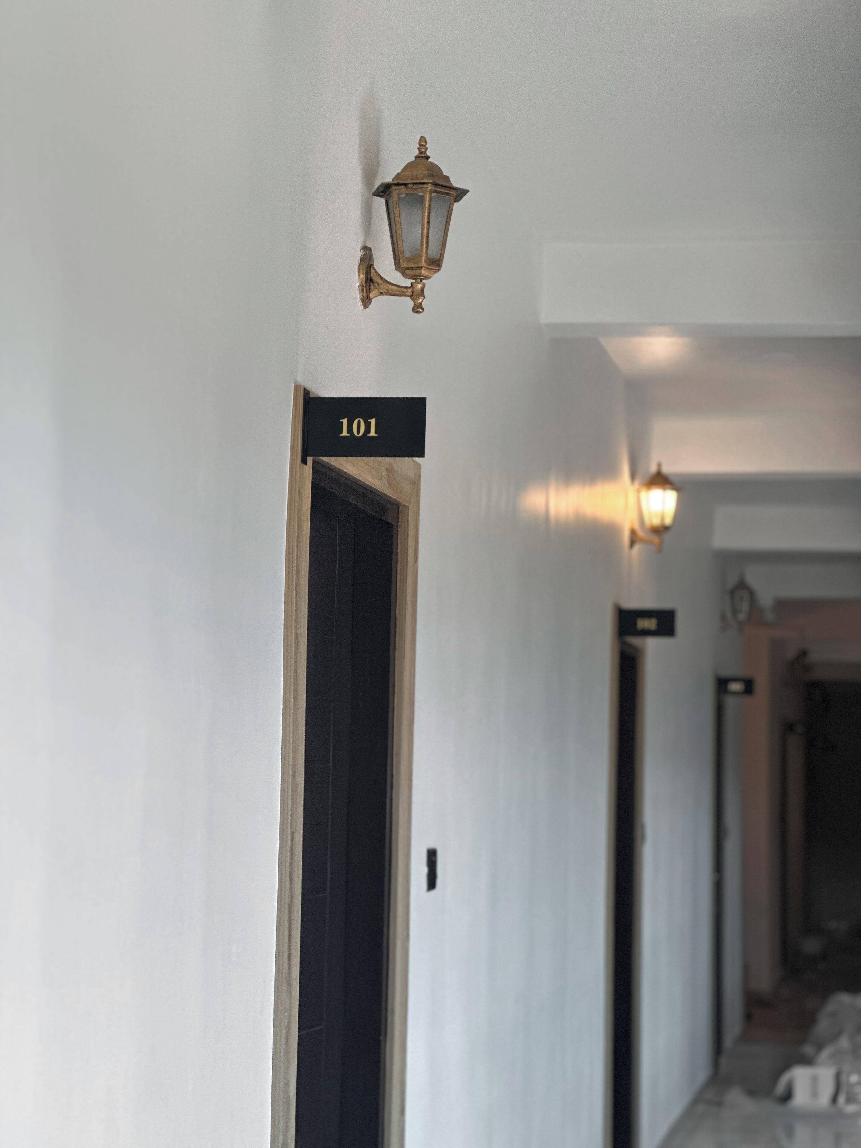 A hallway with a door labeled "101" and a wall-mounted light fixture.