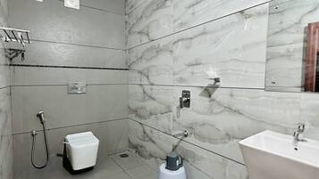 A modern bathroom with a marble wall, a shower, a toilet, and a sink.