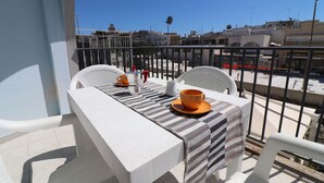 A balcony with a table set for two, a chair, and a view of the cityscape. - Holiday House "idrusa" in Otranto (Otranto)