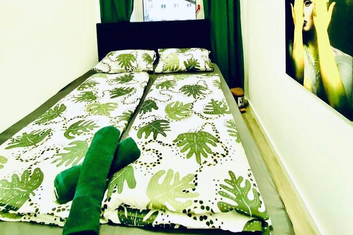 Una habitación pequeña con una cama, una ventana y un cuadro en la pared.
