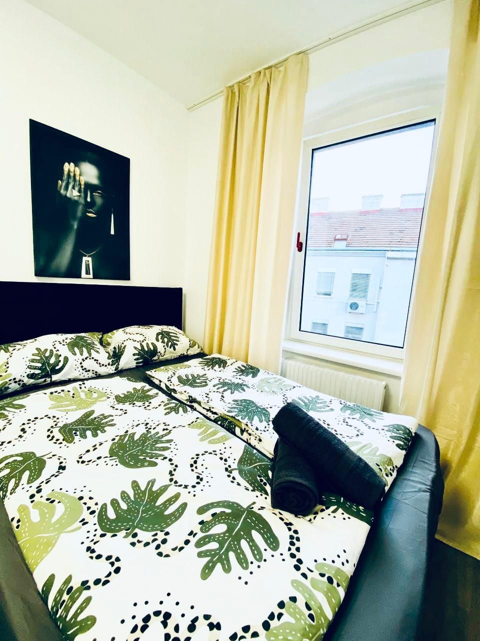 Quarto com cama, janela com cortinas e quadro na parede.