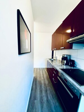 A compact kitchen with dark cabinets, a stainless steel stove, and a coffee maker. - 7BR Apt for 15P Near Schönbrunn (Vienna)