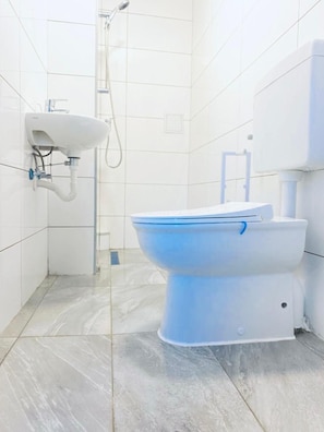 A bathroom with a white toilet, a wall-mounted sink, and a shower. - 7BR Apt for 15P Near Schönbrunn (Vienna)