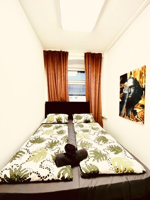 A small, neatly arranged bedroom with a bed, curtains, and a painting on the wall. - 7BR Apt for 15P Near Schönbrunn (Vienna)