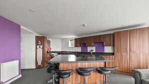 A modern kitchen with a central island, bar stools, and wooden cabinets. - 8 Bed Apartment @ Derriford Stays by Pureserviced (Plymouth)