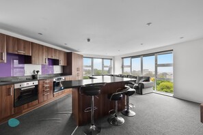 Una cocina moderna con una isla central, taburetes de bar y ventanas amplias con vistas a la ciudad.