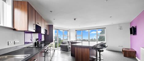 Una cocina moderna con una isla grande, electrodomésticos integrados y vistas al exterior.