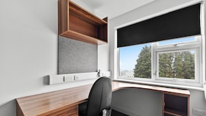A modern office space with a desk, chair, and a window with a view of trees and buildings. - 5 Bed Apartment @ Derriford Stays by Pureserviced (Plymouth)