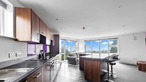 A modern kitchen with a large island, built-in appliances, and a view of the outdoors. - 5 Bed Apartment @ Derriford Stays by Pureserviced (Plymouth)