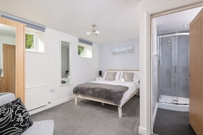 Relax in this serene bedroom with a central bed, wardrobe, and en-suite shower area.