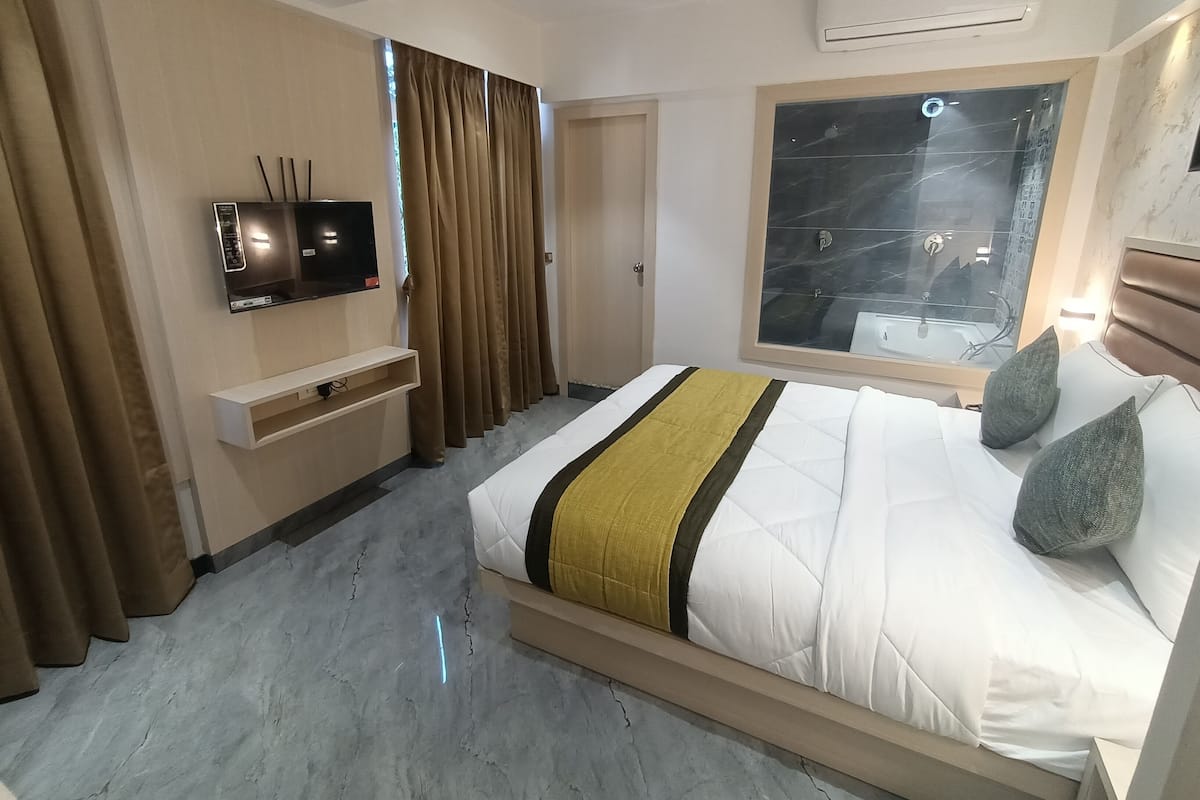 Ein modernes Hotelzimmer mit einem großen Bett, einem an der Wand befestigten Fernseher, einem Fenster mit Blick auf die Stadt und einer Klimaanlage.