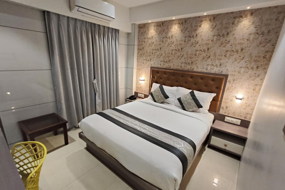 Ein modernes Hotelzimmer mit einem großen Bett, einem Nachttisch, einem kleinen Tisch und einer Klimaanlage.
