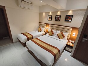 A hotel room with two beds, a wooden headboard, and a wall-mounted air conditioner. - hotel pearl residency (Thane)