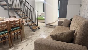 A living room with a sofa, a dining table with chairs, and a staircase. - Boaters' Home 2, Catania (Catania)