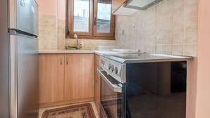 Eine Küche mit Holzausbau, einem Edelstahlkühlschrank, einem Herd und einem Fenster über der Spüle.