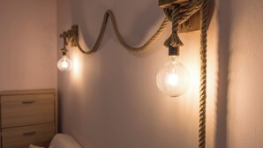 Eine Wandleuchte mit Kordeldesign, ein Nachttisch aus Holz und eine Schublade.