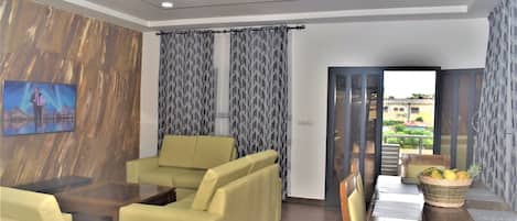 Relax in a stylish room with a sofa, armchairs, and a large flat-screen TV.