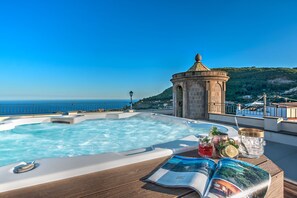 Un jacuzzi sur une terrasse avec vue sur la mer et une petite structure en forme de tour.
