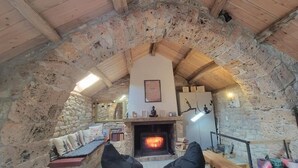Une pièce chaleureuse avec une cheminée en pierre, des poutres en bois et un banc en pierre.