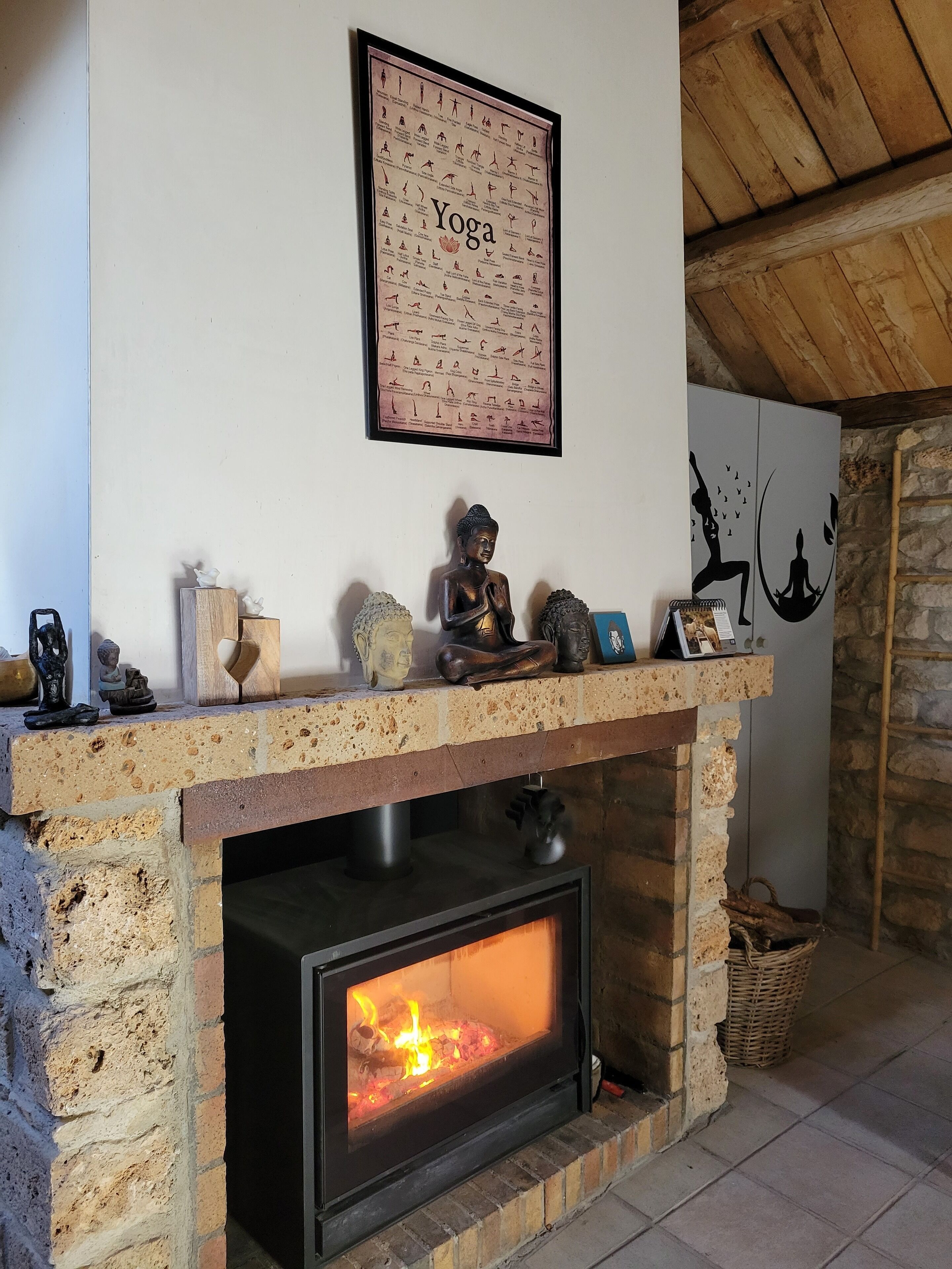 Une cheminée avec un feu, une affiche de yoga et divers objets décoratifs sur la manteau de cheminée.