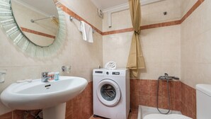 A bathroom with a sink, a washing machine, a toilet, and a shower area. - Mytilene Central Home 1 (Mitilini)
