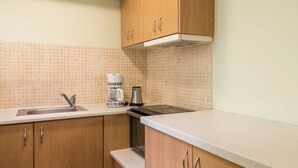 A kitchen with wooden cabinets, a stainless steel sink, a coffee maker, and a built-in oven. - Mytilene Central Home 1 (Mitilini)