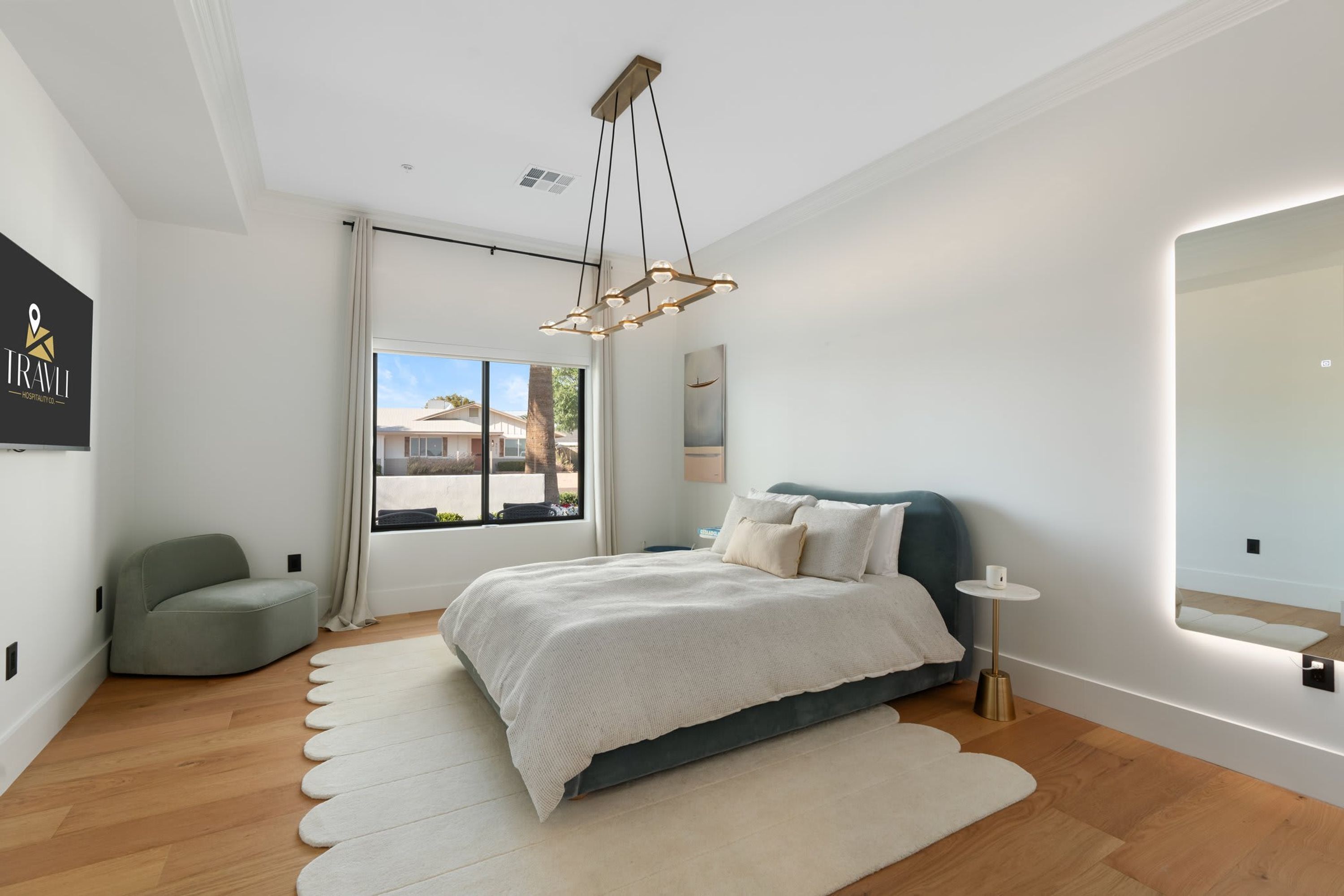 Un dormitorio moderno con cama, mesita de noche, silla, ventana grande y lámpara de techo.