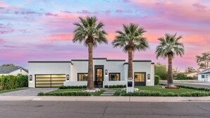 A modern two-story house with a garage, palm trees, and a well-maintained lawn. - NEW The Casa Privada Experience (Scottsdale)
