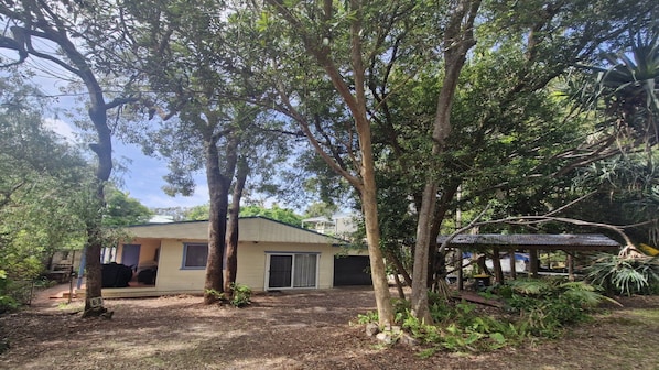 A house with a covered porch, surrounded by trees and a garden.