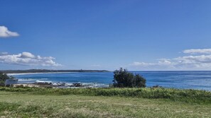 A coastal landscape with a clear sky, a beach, and a grassy foreground.