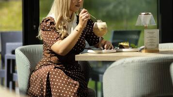 A person seated at a table with a menu, a drink, and a dessert.