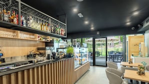 Uma área de bar moderna com balcão de madeira, prateleiras cheias de garrafas e uma vitrine de vidro.