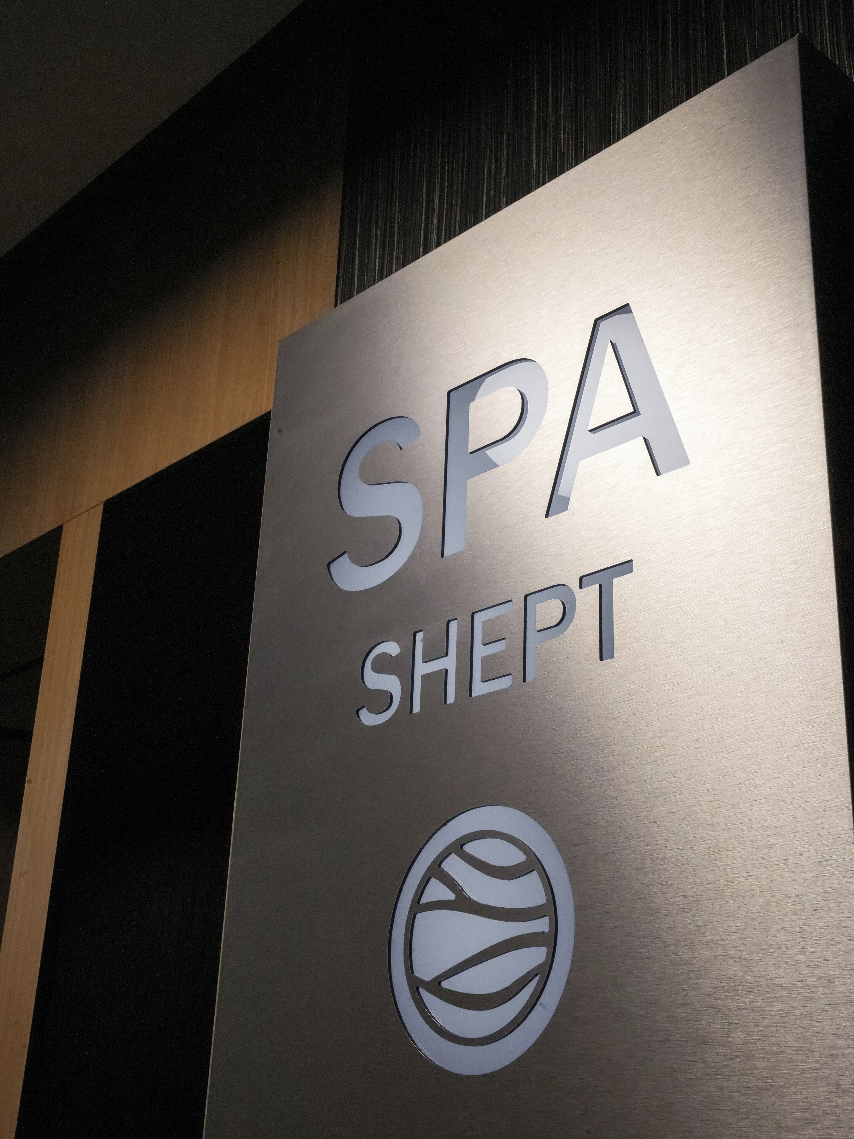 Une enseigne métallique portant l’inscription « SPA SHEPT » et un logo stylisé.