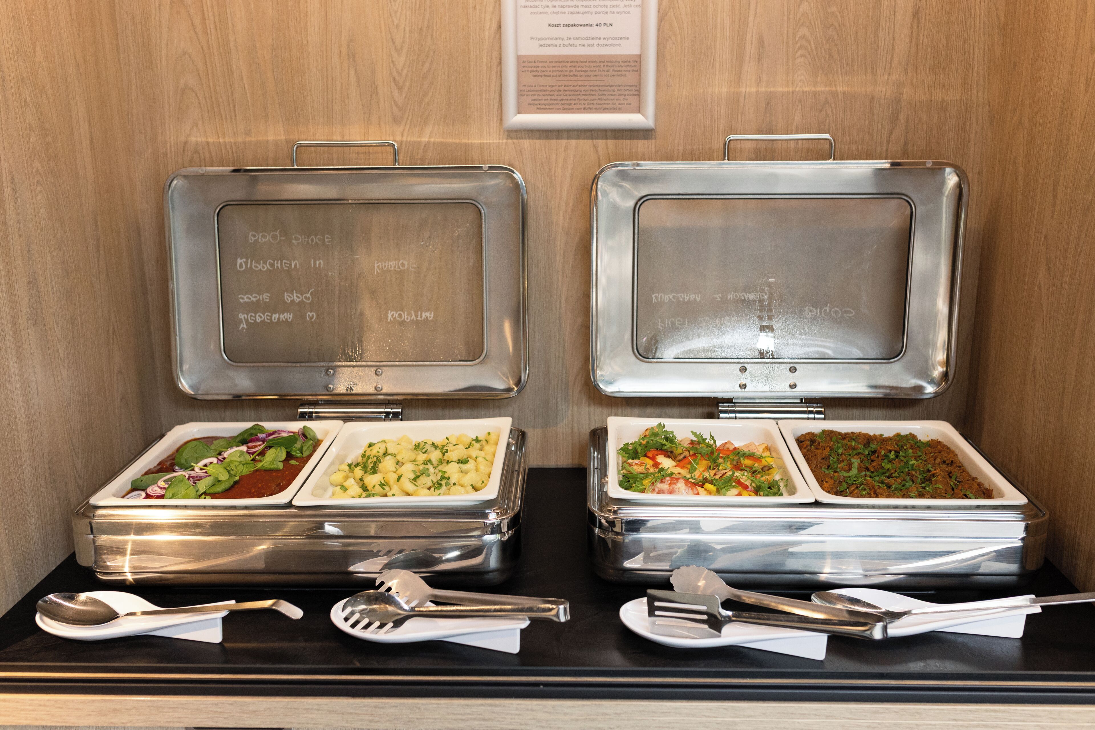 Two buffet stations with food containers and serving utensils.