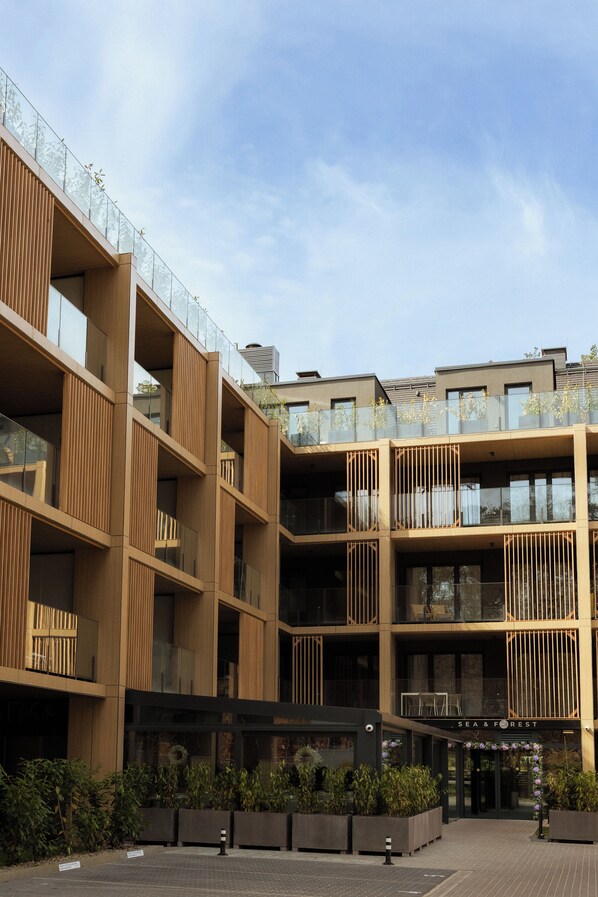 Un edificio de varios pisos con balcones, un patio central con jardineras y un letrero que dice 'SEA & FOREST'.
