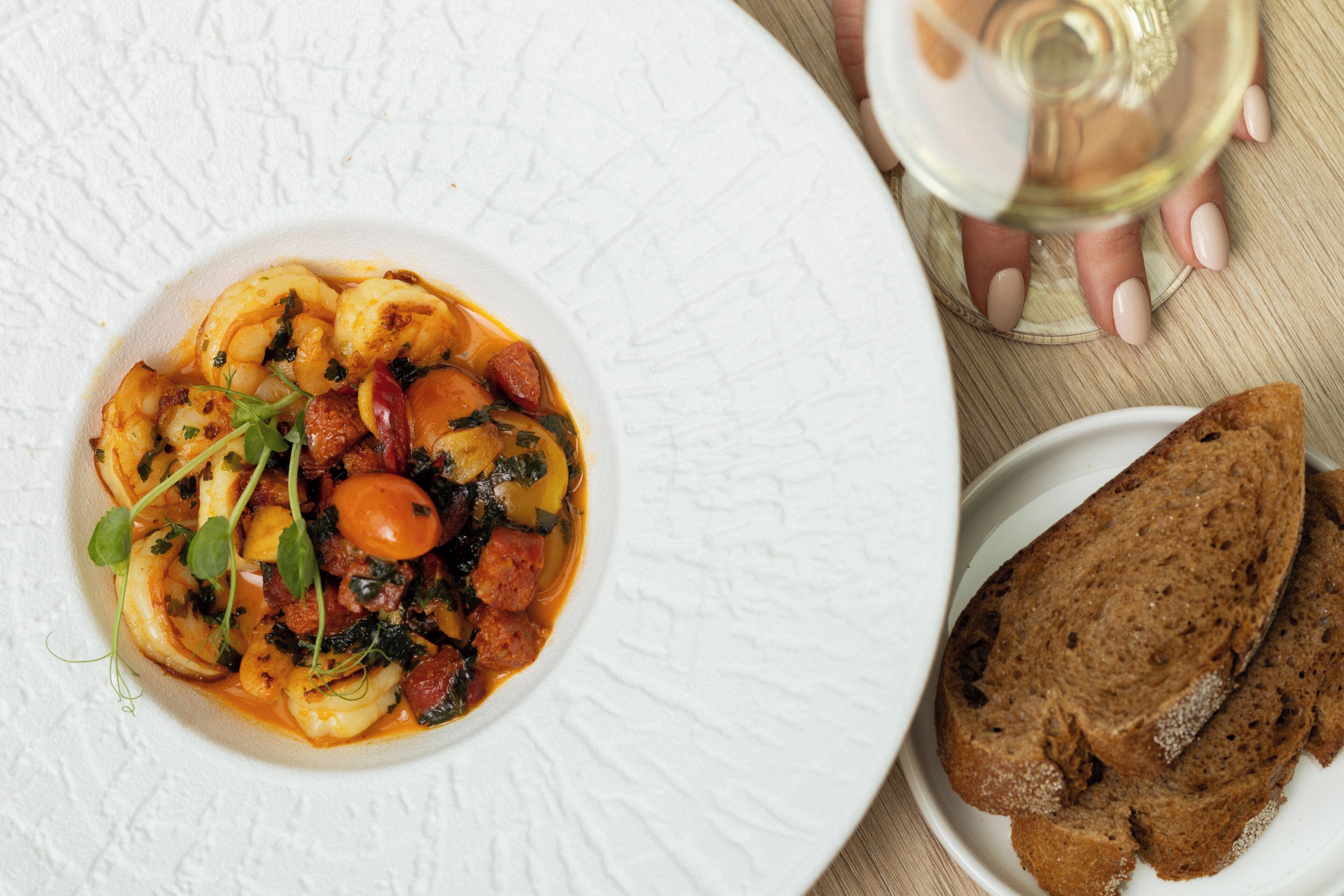 A plate of food with bread and a glass of wine on a table.