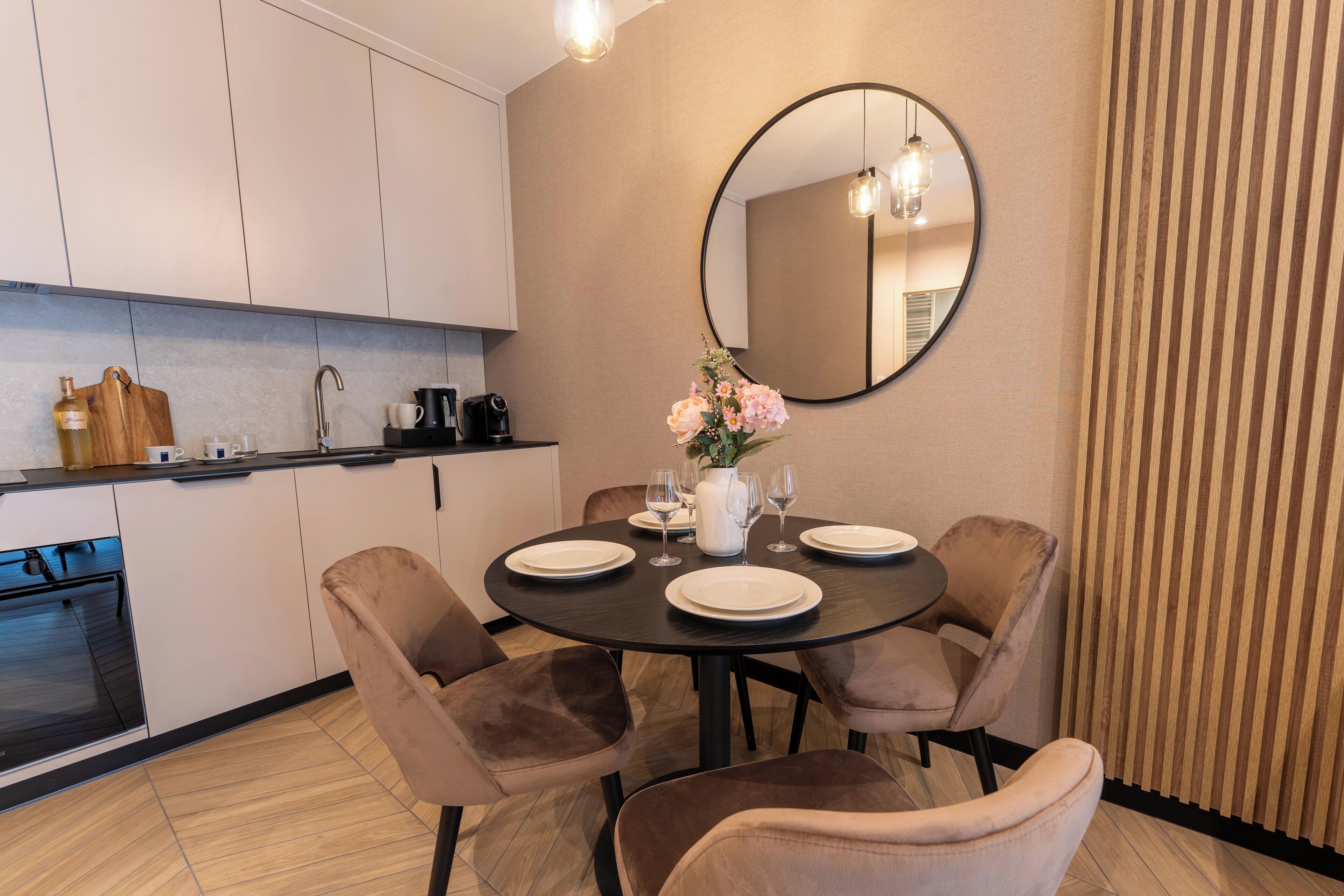 A modern kitchen with white cabinets, a black countertop, and a dining area with a round table set for four.