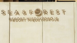 Um edifício de vários andares com varandas e um letreiro com a inscrição 'SEA & FOREST RESORT MEDYZDROJE'.