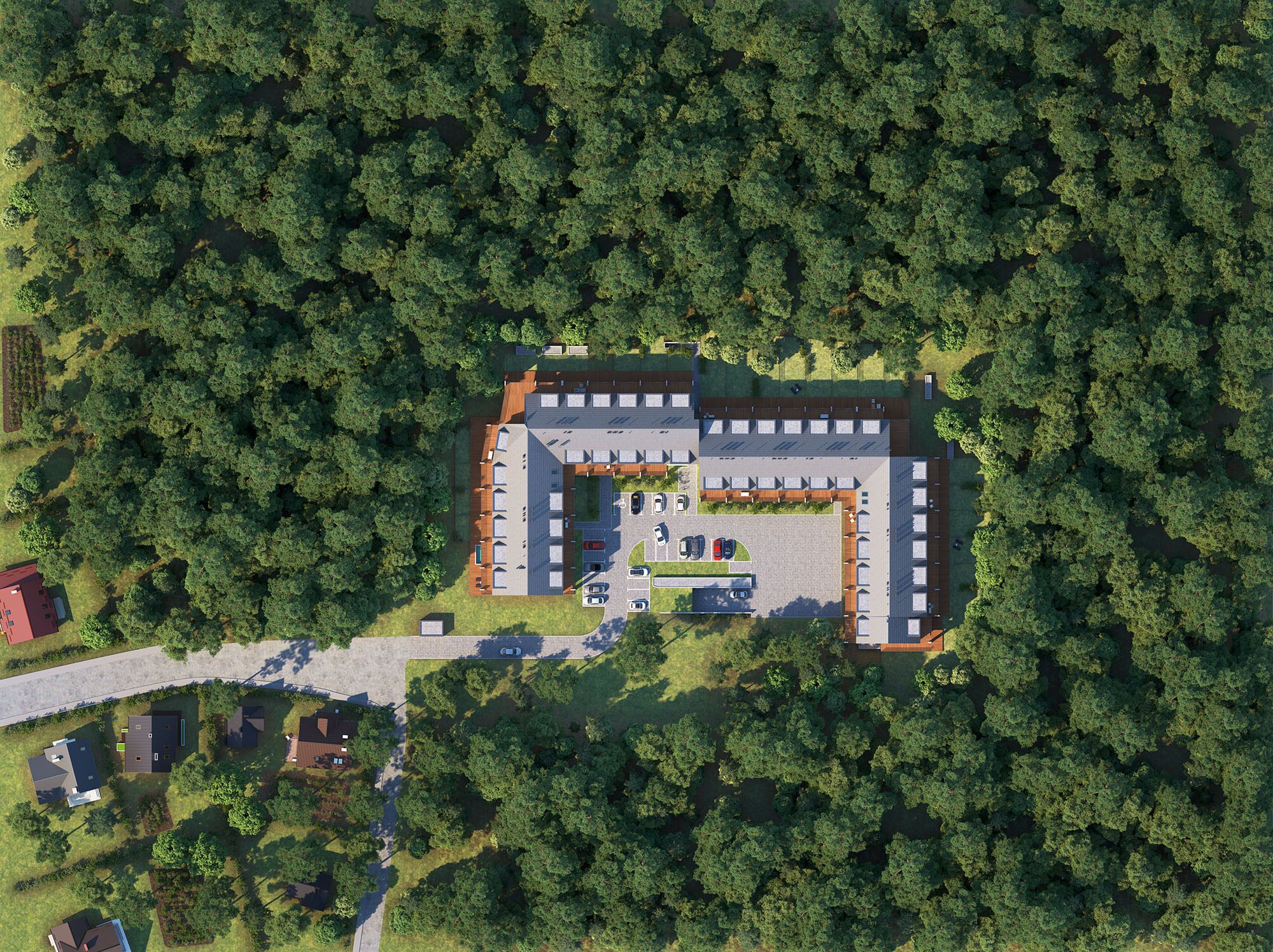 An aerial view of a building surrounded by dense forest, featuring a parking lot, multiple buildings, and a clear road entrance.