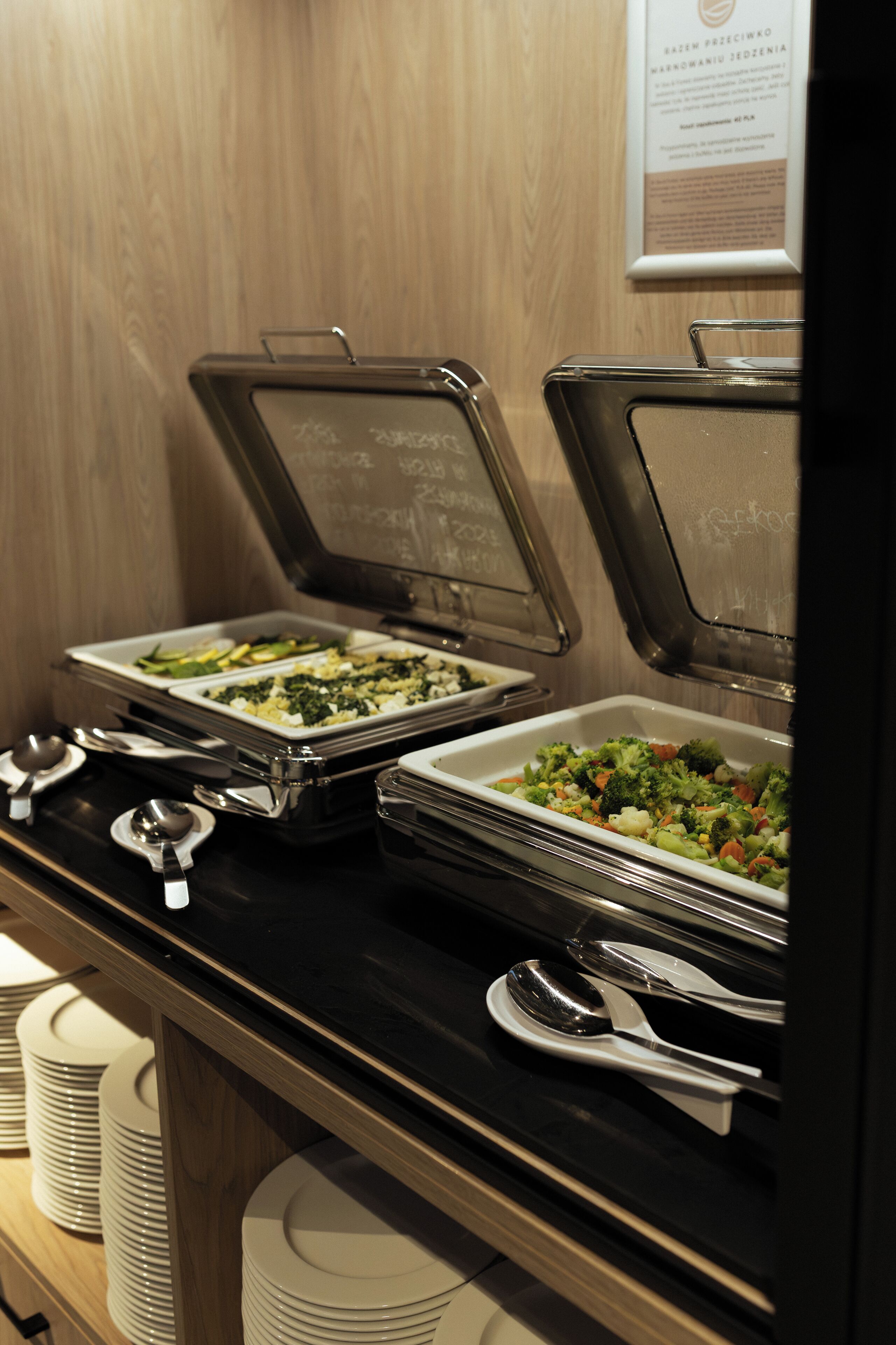 Buffet-style food service with trays of vegetables and a variety of dishes.