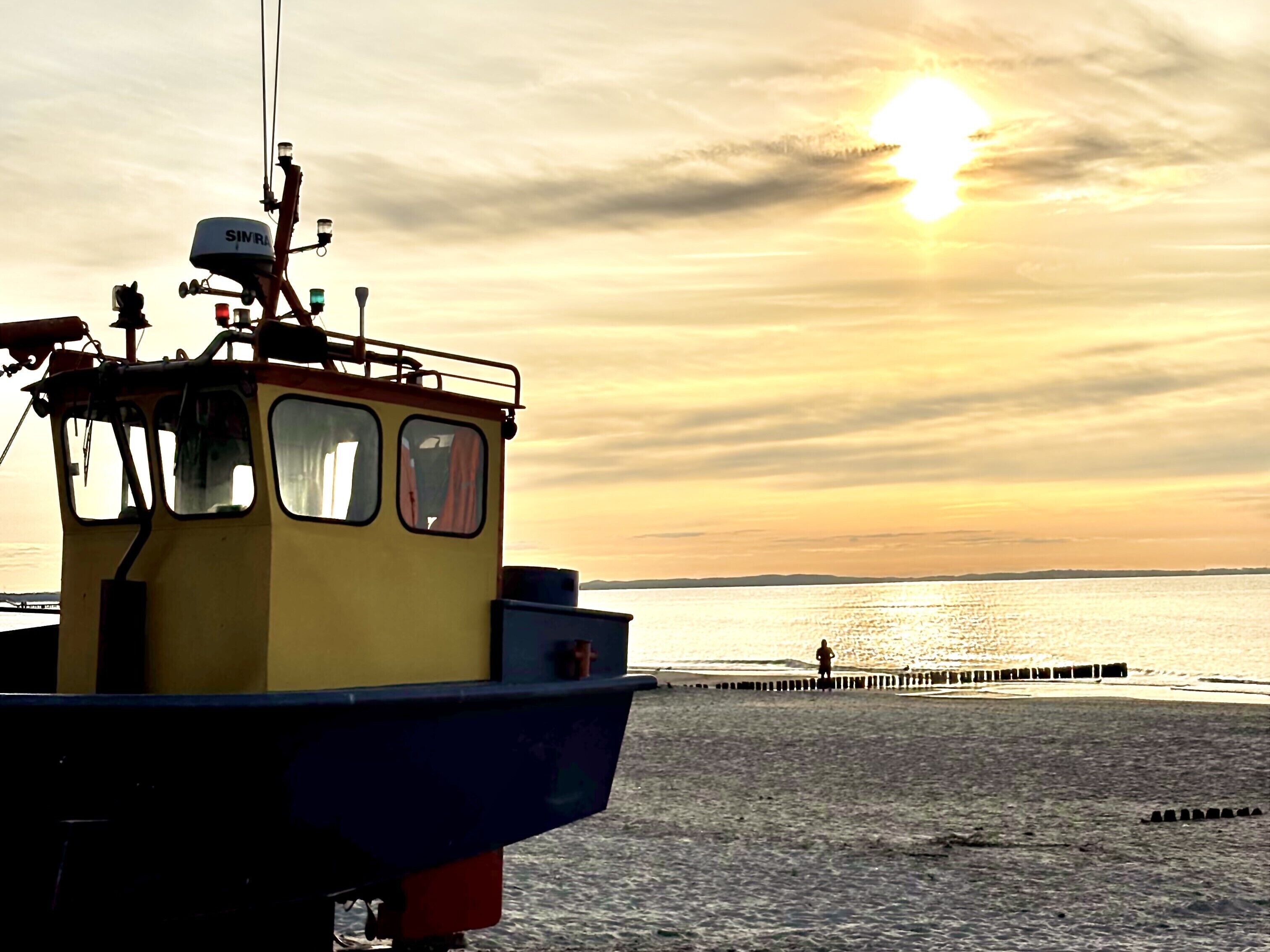 A boat docked at a pier with a sunset in the background.