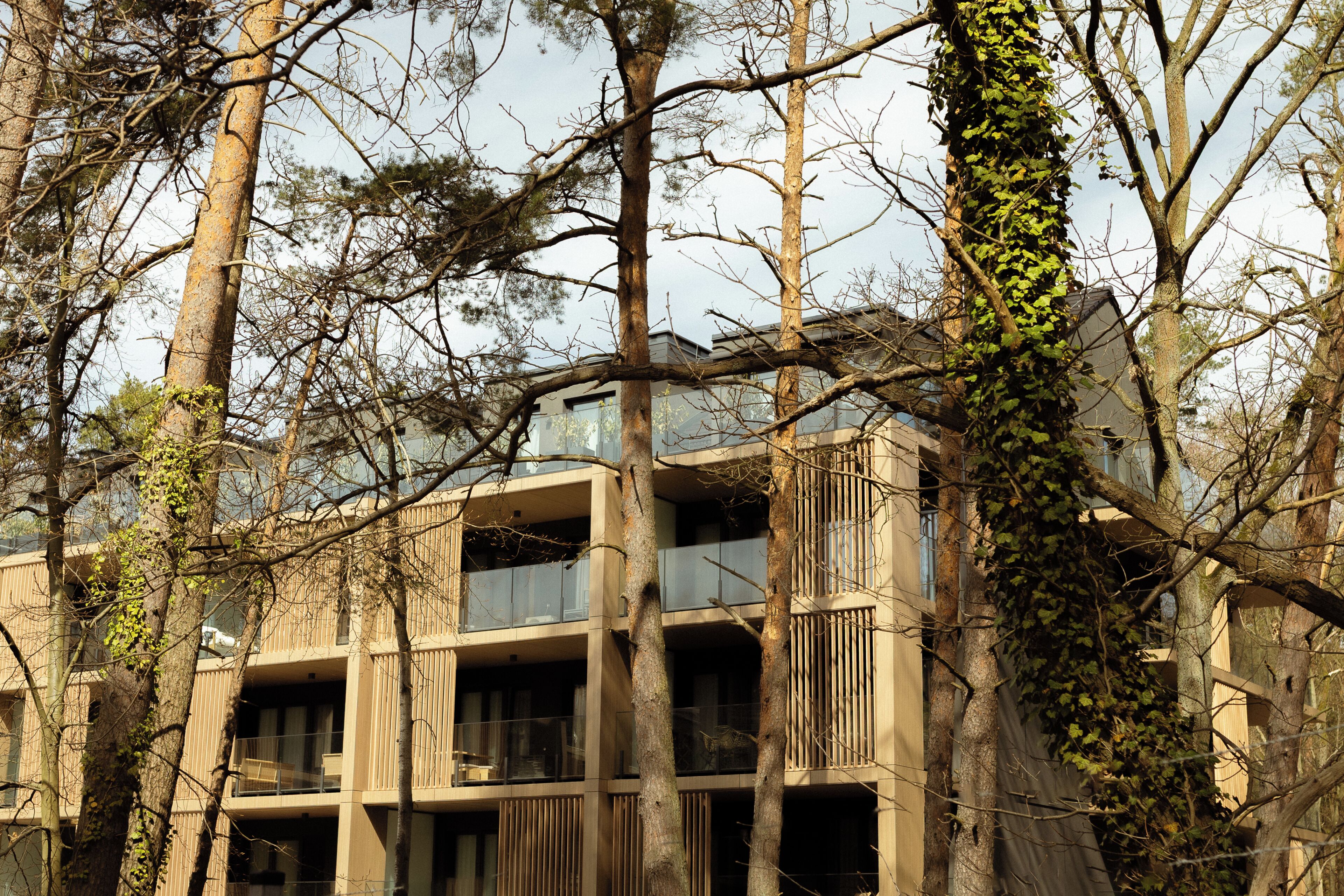 A multi-story building with balconies, surrounded by trees and vines.