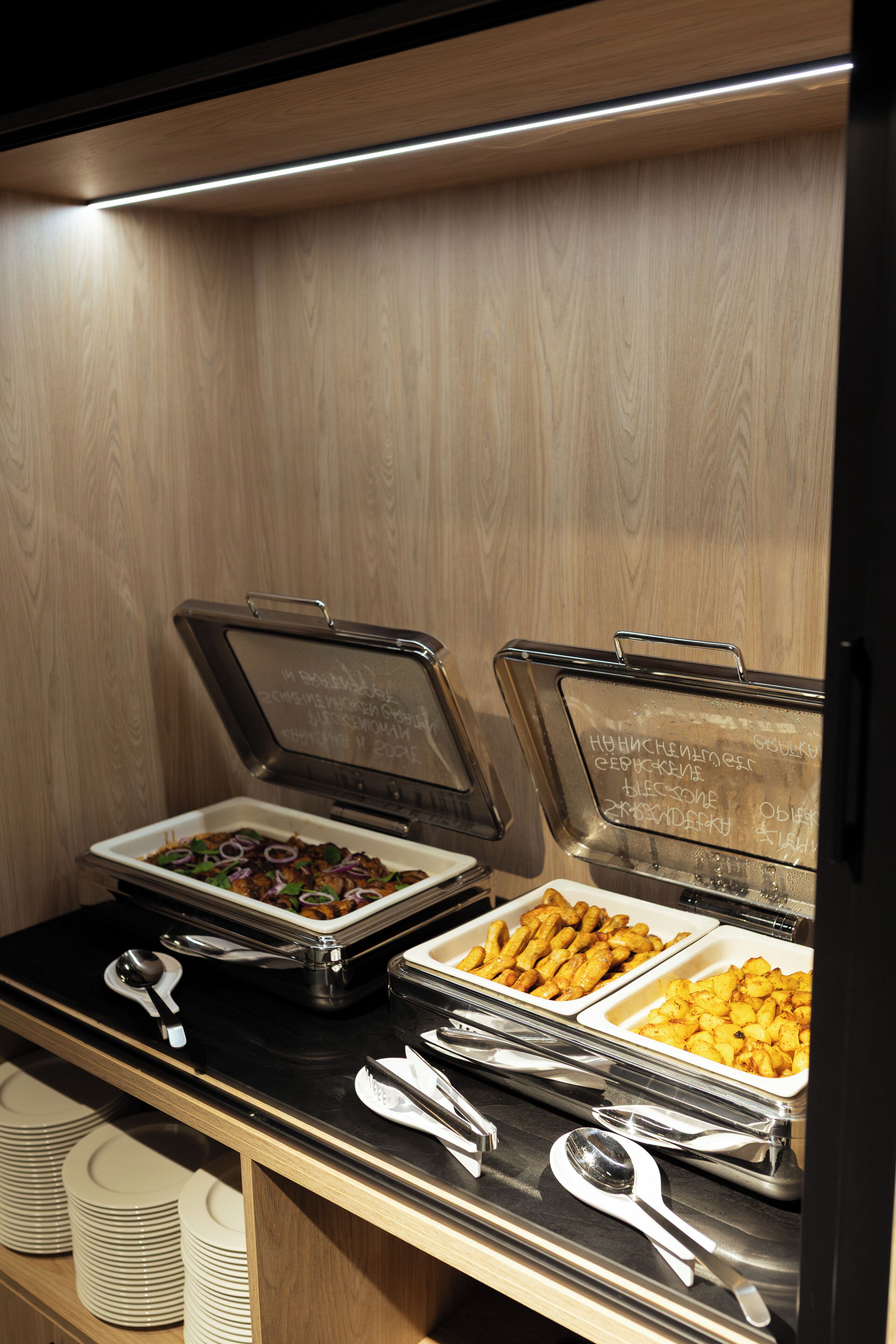 A buffet setup with various food items and serving utensils.