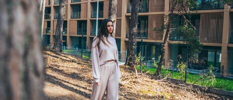 Una persona de pie sobre un sendero, con árboles y un edificio moderno al fondo.