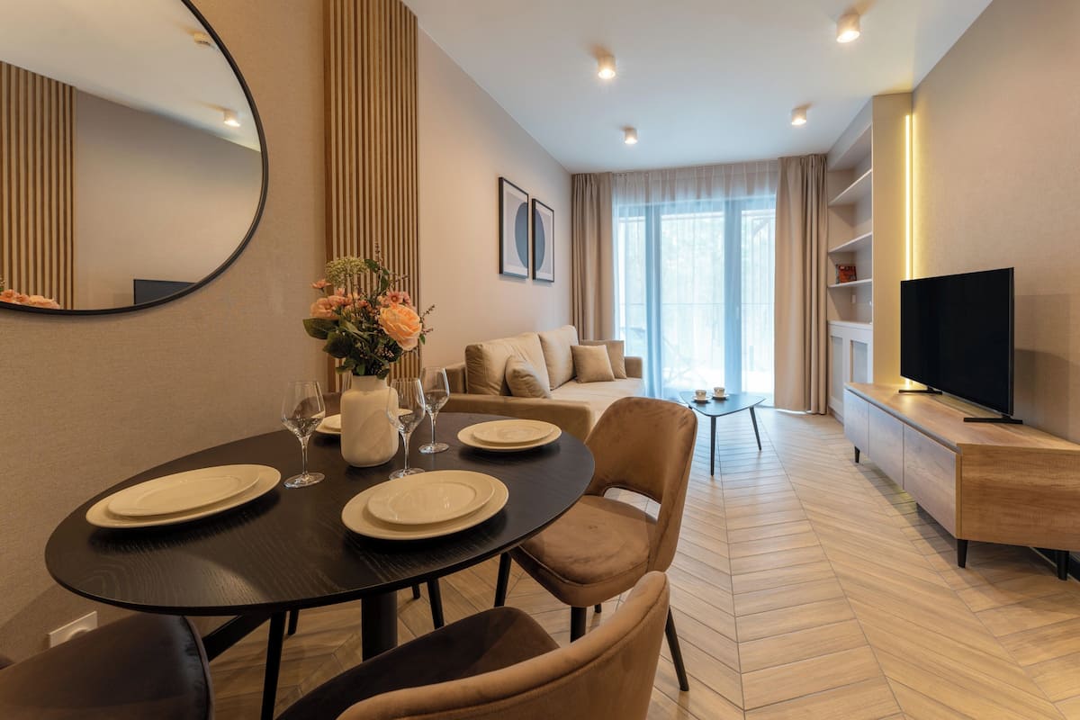 A modern living room with a dining area, a sofa set, a TV, and a large mirror.